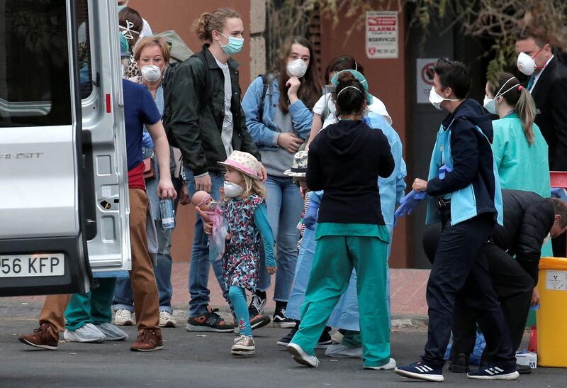 Health personnel wearing protection clothing assist guests as they leave the H10 Costa Adeje Palace hotel in La Caleta, in the Canary Island of Tenerife, Spain, Friday Feb. 28, 2020. Some guests have started to leave the locked down hotel after undergoing screening for the new virus that is infecting hundreds worldwide. (AP Photo/Joan Mateu)