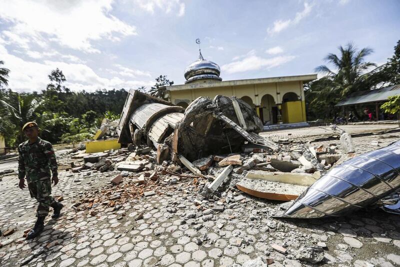 An Indonesian soldier inspects a collapsed mosque after the earthquake. Hotli Simanjuntak / EPA