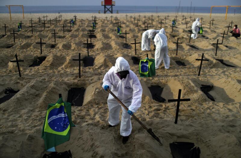 FILE PHOTO: Activists of the NGO Rio de Paz in protective gear dig graves on Copacabana beach to symbolise the dead from the coronavirus disease (COVID-19) during a demonstration in Rio de Janeiro, Brazil, June 11, 2020. REUTERS/Pilar Olivares/File Photo