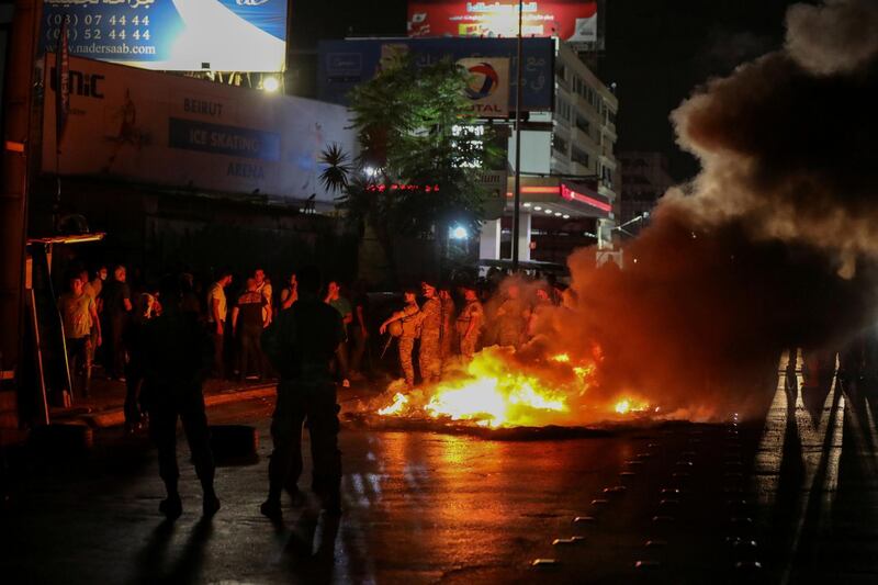 Lebanese army soldiers stand guard as smoke rises from tires set on fire by demonstrators during a protest, after Lebanon's Central Bank said it would stop bank withdrawals from dollar accounts at a low fixed rate, in Antelias, Lebanon. Reuters