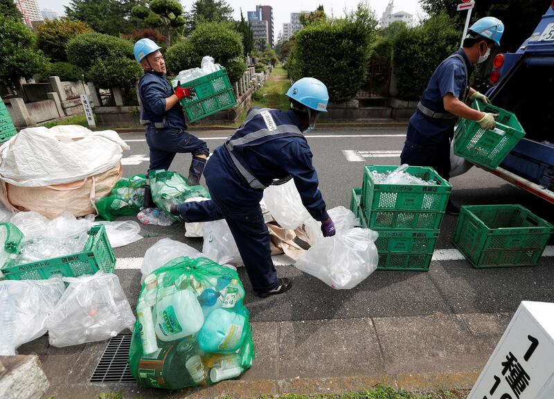 Workers collect recyclable garbage including cans, plastic trays and plastic or glass bottles on the street  in Tokyo, Japan.  REUTERS