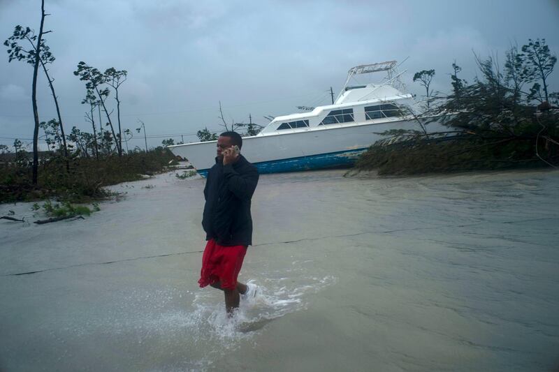 A man talks on his mobile phone next to a catamaran that was thrown onshore. AP