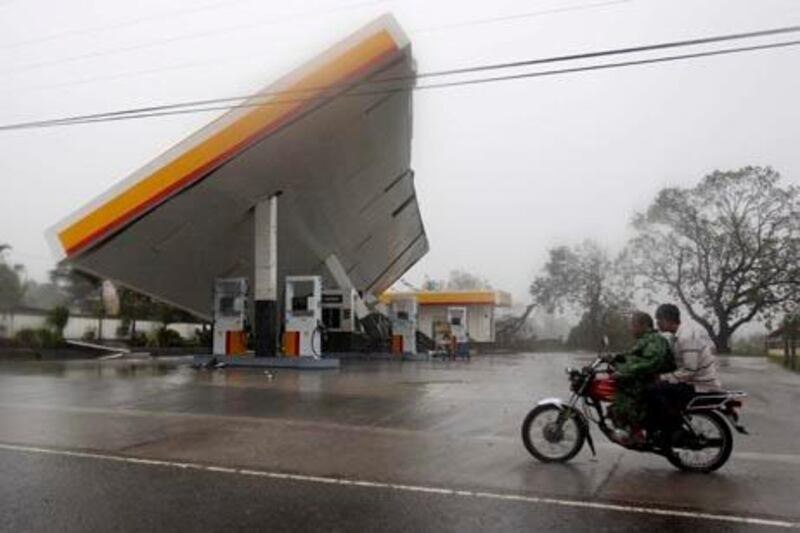 ** CORRECTS YEAR ** Motorists drive past a filling station which was toppled by typhoon Megi (local name "Juan") Monday Oct.18, 2010 at Cauayan, Isabela province in northeastern Philippines. The strongest cyclone in years to buffet the Philippines knocked out communications and power as residents took shelter Monday. (AP Photo/Bullit Marquez)