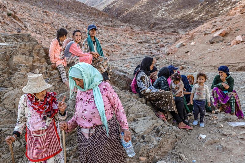 Survivors sit on rocks on the side of a hill. AFP