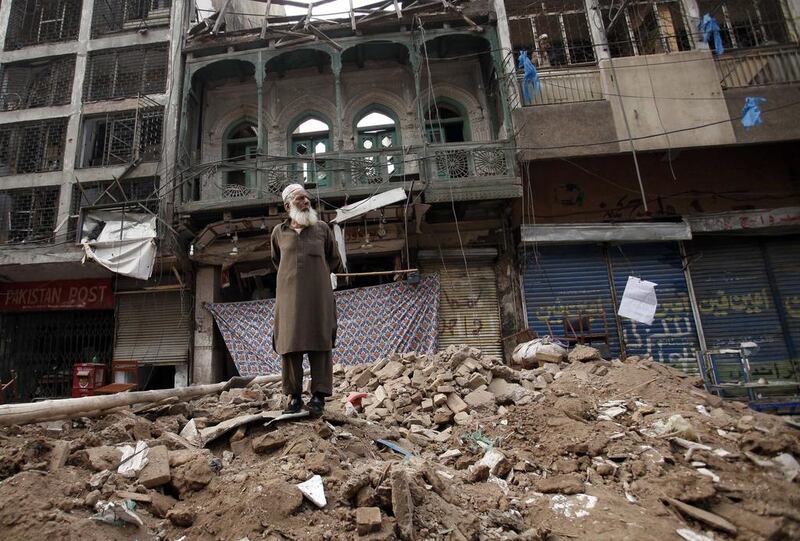 A man stands on a pile of rubble in front of a damaged building after it was hit by a bomb blast on Sunday, in Peshawar. The death toll from a car bomb explosion in an ancient market in Pakistan’s northwestern city rose to at least 42 on Monday. Fayaz Aziz/Reuters