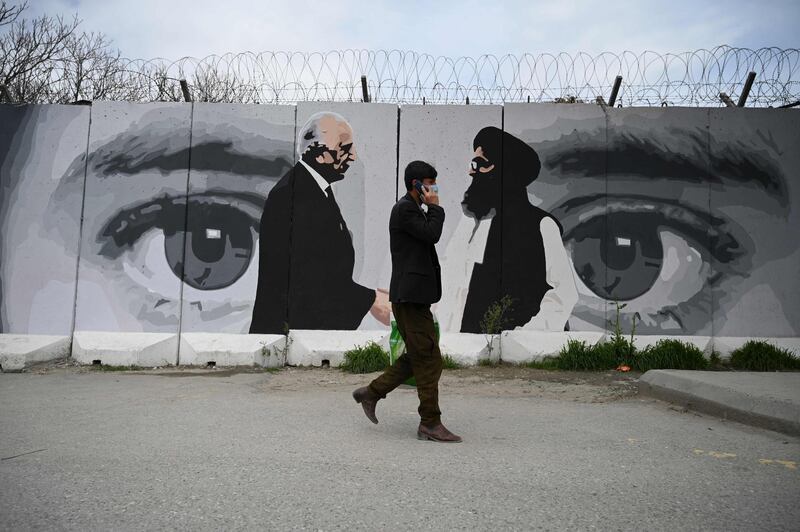 A man wearing a facemask walks past a wall painted with images of US Special Representative for Afghanistan Reconciliation Zalmay Khalilzad and Taliban co-founder Mullah Abdul Ghani Baradar, in Kabul. AFP
