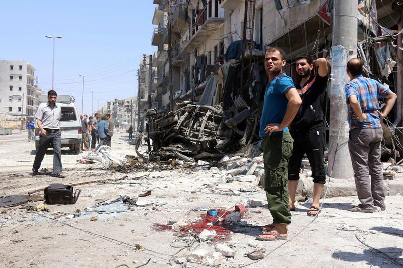 Syrians stand next to debris following bombardment by government forces on the Salhin district of the northern city of Aleppo on July 21, 2016. The United Nations on THursday issued an urgent plea for weekly 48-hour truces in Aleppo, where at least a quarter of a million civilians are now trapped by a government siege. Thaer Mohammed/AFP

