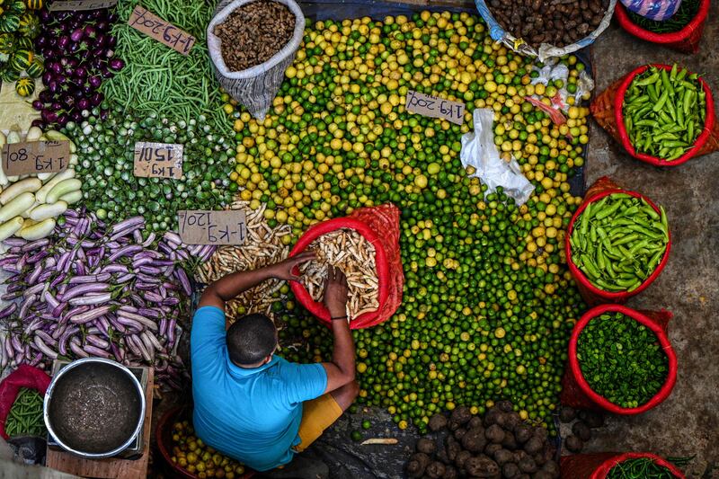 A vendor arranges vegetables as he waits for customers at a market in Colombo, Sri Lanka. AFP