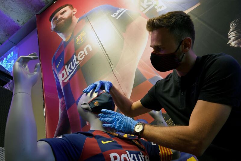 An employee places a mask with the logo of FC Barcelona on a mannequin at the FC Barcelona store. AFP