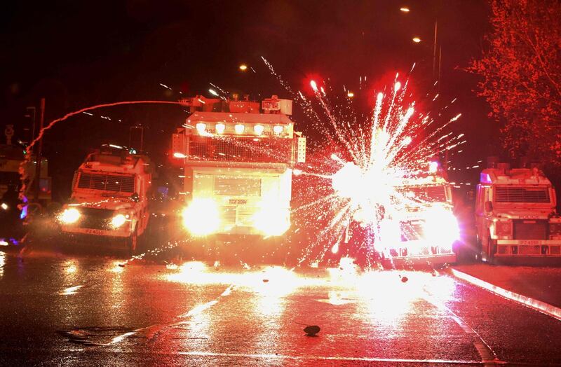 Fireworks explode by police vehicles after being fired at police officers in the Springfield Road area of Belfast. AFP