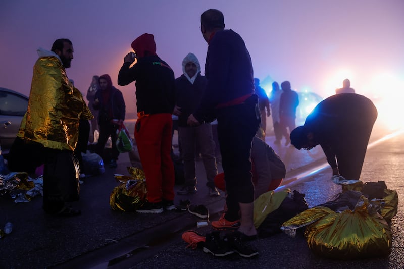 Migrants warm themselves in Boulogne-sur-Mer, France, after being rescued by a French vessel from the English Channel, on Tuesday. Reuters