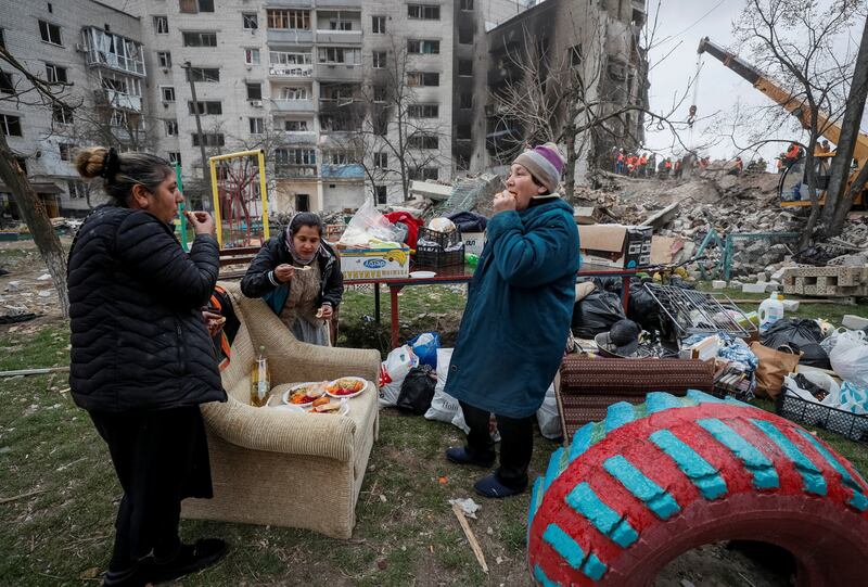 Local residents eat free food near their house, destroyed by Russian shelling, in Borodyanka, in Ukraine's Kyiv region. Reuters