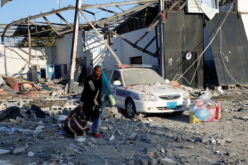 FILE PHOTO: A migrant picks up her belongings from among rubble at a detention centre for mainly African migrants that was hit by an airstrike in the Tajoura suburb of the Libyan capital of Tripoli, Libya July 3, 2019. REUTERS/Ismail Zitouny/File Photo