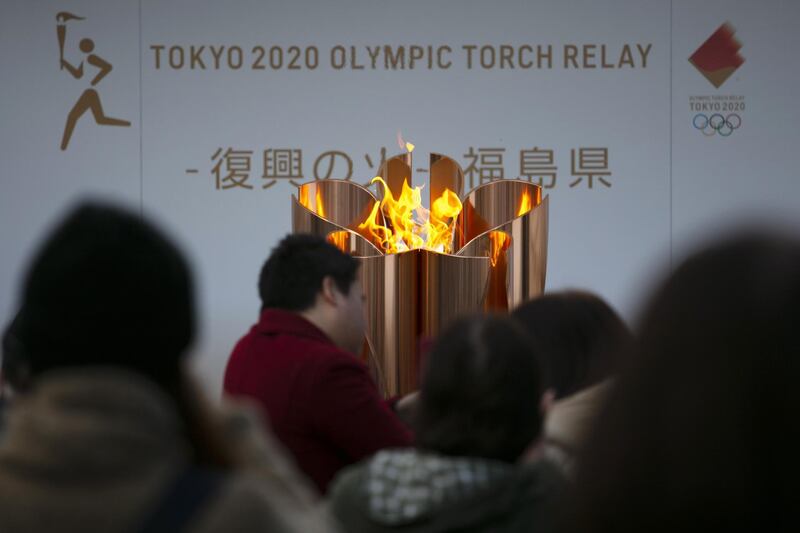 The Olympic Flame burns as people wait in line. AP