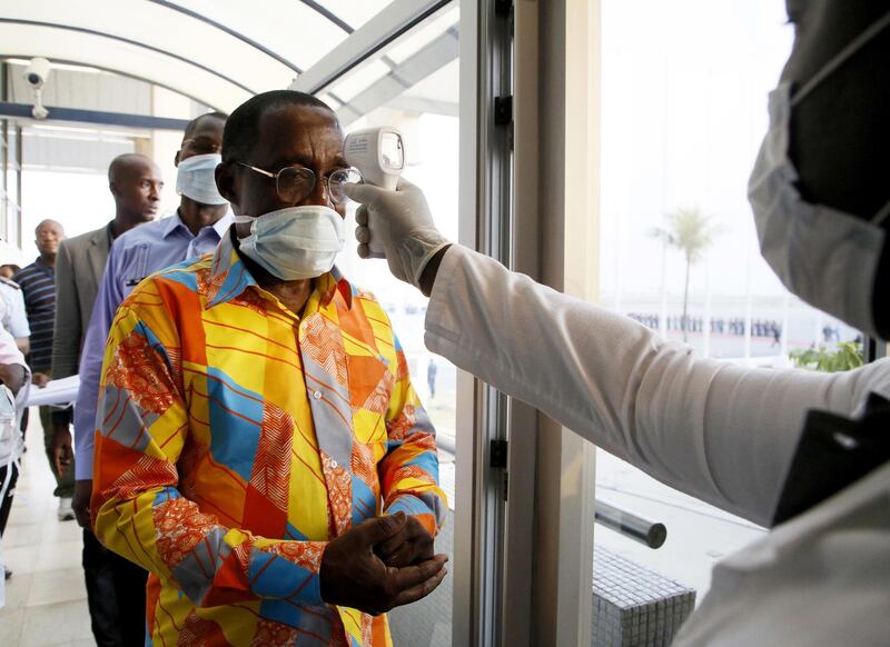An Ivorian health worker from the National Institute of Public Hygiene checks the temperature of Ivorian Minister of Health and Public Hygiene Aka Aoule (L) during the establishment of security measures to curb the spread of Coronavirus at Felix Houphouet-Boigny Airport, Abidjan, Ivory Coast.  EPA