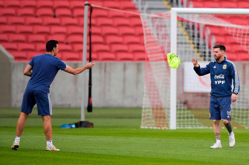 Argentina manager Lionel Scaloni throws a vest to  Lionel Messi during a training session. AFP