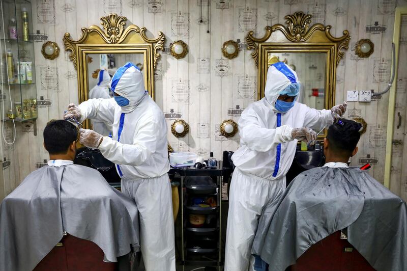 Barbers wearing protective suits and face masks provide hair cut service to the customers inside a salon amid the coronavirus disease (COVID-19) outbreak, in Dhaka, Bangladesh. Reuters