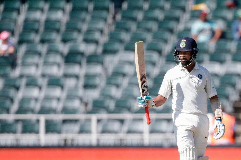 Indian batsman Cheteshwar Pujara raises his bat as he celebrates scoring a half-century (50 runs) during the first day of the third test match between South Africa and India at Wanderers cricket ground on January 24, 2018 in Johannesburg. / AFP PHOTO / GIANLUIGI GUERCIA