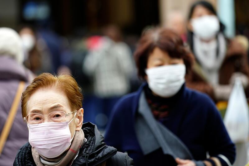 Pedestrians wear protective masks as they walk through a shopping district in Tokyo Thursday, Jan. 16, 2020. Japan's government said Thursday a man treated for pneumonia after returning from China has tested positive for the new coronavirus identified as a possible cause of an outbreak in the Chinese city of Wuhan. (AP Photo/Eugene Hoshiko)