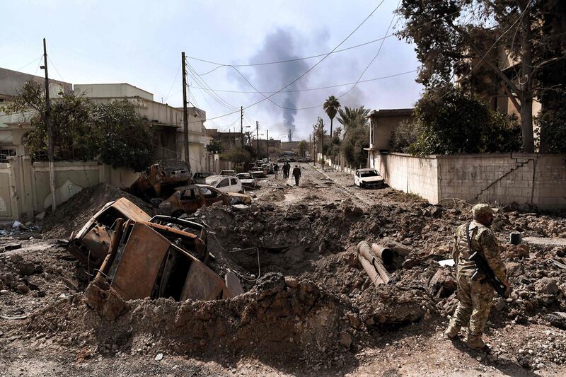 An Iraqi forces member stands next to a crater from an air strike in west Mosul during the battle to retake the city from ISIS in March 2017. AFP