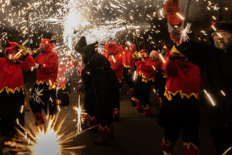 Revellers dressed as devils hold torches with firecrackers as they take part in a fire-run during the Sant Antoni festival in Barcelona, Spain.  Getty