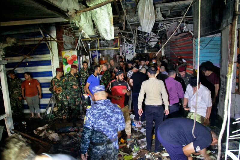 People and security forces gather at the site of a bombing in Wahailat market in Sadr City, Iraq, Monday, July.  19, 2021.  A roadside bomb attack targeted a Baghdad suburb Monday, killing several and wounding dozens of others at a crowded market, Iraqi security officials said.  (AP Photo / Khalid Mohammed)