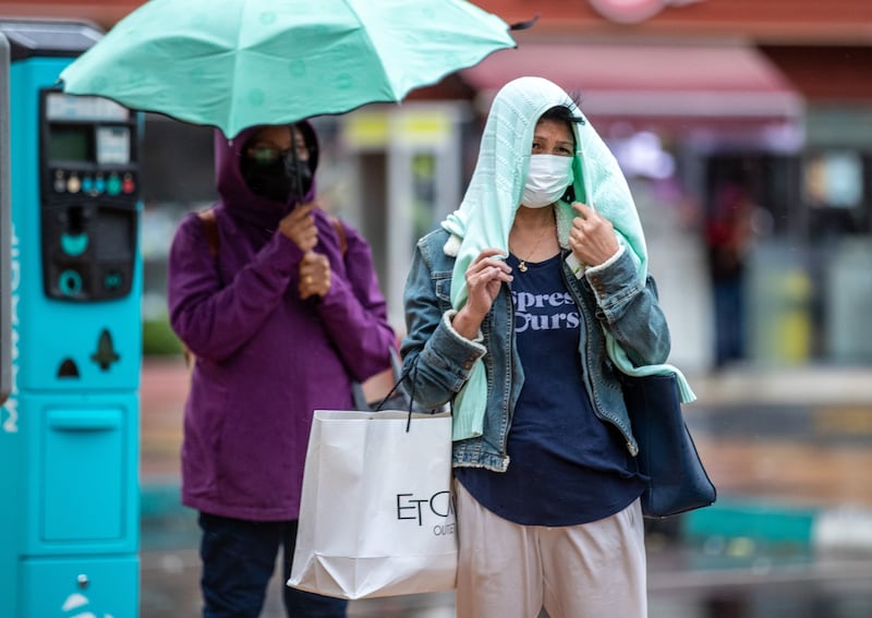 Women make their way amid the rains. Victor Besa / The National