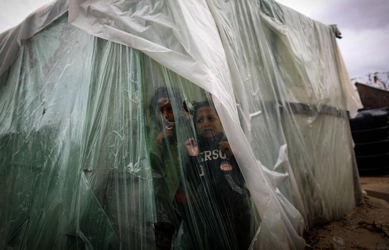 Palestinian children watch the rain from behind nylon sheets covering their family tent, on a rainy day in al-Amal (hope in Arabic) neighbourhood of Beit Lahia in the northern Gaza Strip.  AFP