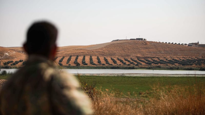 This picture taken on October 26, 2019 from a position near the village of Awshariyah south of Jarabulus in the northern part of Aleppo province, held by Turkey-backed Syrian forces, shows one of the fighters looking at a Syrian government forces military position across the Sajur river that joins with the Euphrates.  / AFP / Aaref WATAD
