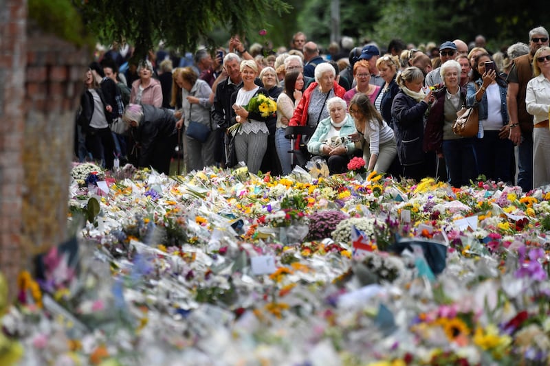 Mourners view the flowers. AFP