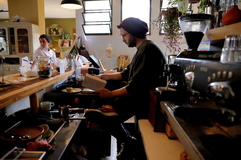 The atmosphere in cafes is often hushed and almost studious, with many people using the venues to work online or read a book, as this barista is doing.