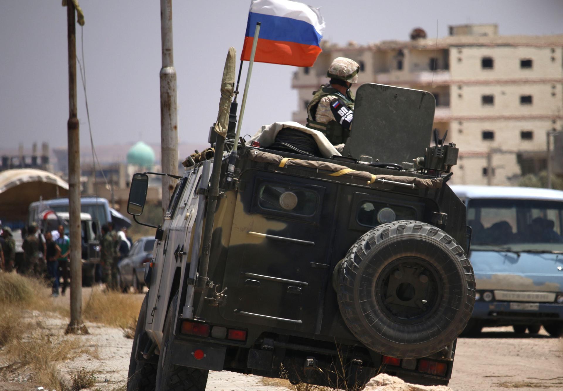 A Russian soldier on his armoured vehicle watches Syrian rebels during evacuation from Daraa city, on July 15, 2018, as Syrian government forces heavily bombed the neighbouring province of Quneitra making a ground advance in the zone.  
 


 Syrian rebels and their relatives began evacuating the southern city of Daraa today under a deal to bring the "cradle" of the country's uprising back into the government's fold. / AFP / Mohamad ABAZEED
