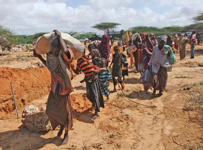 Somalis from southern Somalia carrying their belongings make their way to the new camp in southern Mogadishu's Hosh neighborhood Tuesday, July 12, 2011. Thousands of people have arrived in Mogadishu over the past two weeks seeking assistance and the number is increasing by the day, due to lack of water and food. The drought in the Horn of Africa has sparked a severe food crisis and high malnutrition rates, with parts of Kenya and Somalia experiencing pre-famine conditions, the United Nations has said. More than 10 million people are now affected in drought-stricken areas of Djibouti, Ethiopia, Kenya, Somalia and Uganda and the situation is deteriorating. (AP Photo/Farah Abdi Warsameh) . 