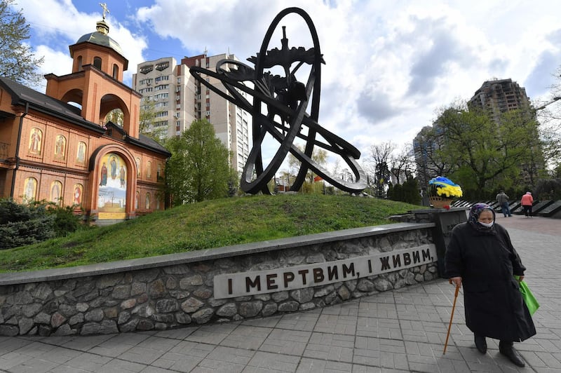 An elderly woman wearing a face mask visits Chernobyl's memorial in Kiev to commemorate the victims on the 34th anniversary of the tragedy.  AFP