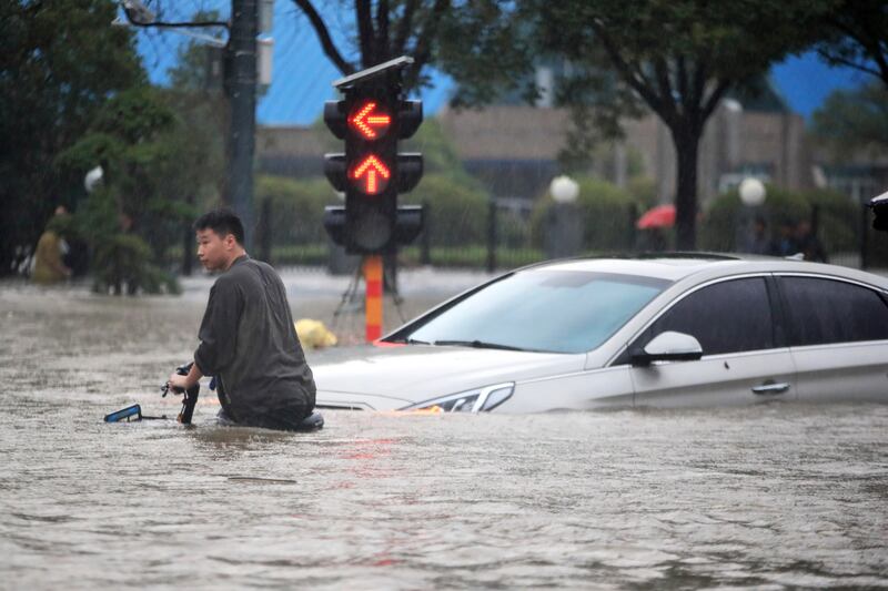 A man struggles with his bike on a flooded road after record downpours in Zhengzhou city in central China's Henan province.