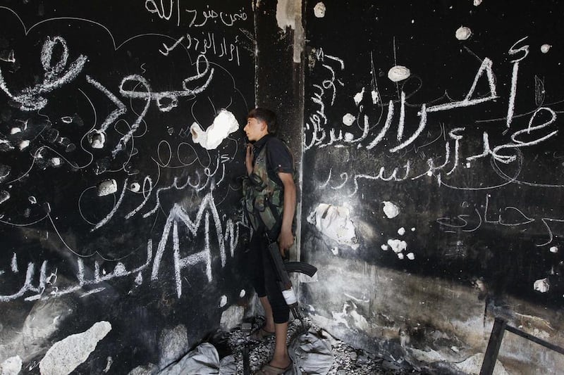 A Free Syrian Army fighter holds his weapon as he looks through a hole in the wall in the Al Khalidiya neighbourhood of Aleppo. Muzaffar Salman / Reuters