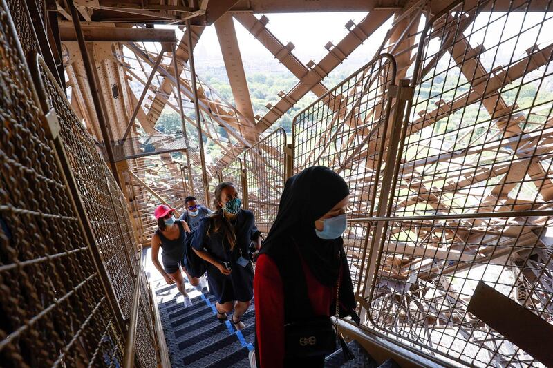 Visitors wearing protective face masks walk the stairs as they visit the Eiffel Tower during its partial reopening, in Paris. AFP