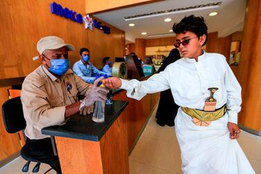 A security guard wearing a protective mask sprays sanitiser onto the hands of incoming customers as a measure against Covid-19 in Yemen's capital Sanaa. AFP