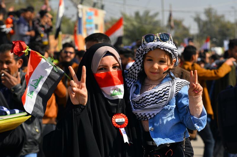 An Iraqi woman carrying a child, flashes the V-sign for victory during anti-government protests in the Shiite shrine city of Najaf in central Iraq. AFP