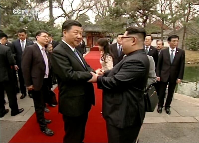 North Korean leader Kim Jong Un, right, and Chinese counterpart Xi Jinping, left, shake hands  at Diaoyutai State Guesthouse in Beijing. CCTV via AP Video
