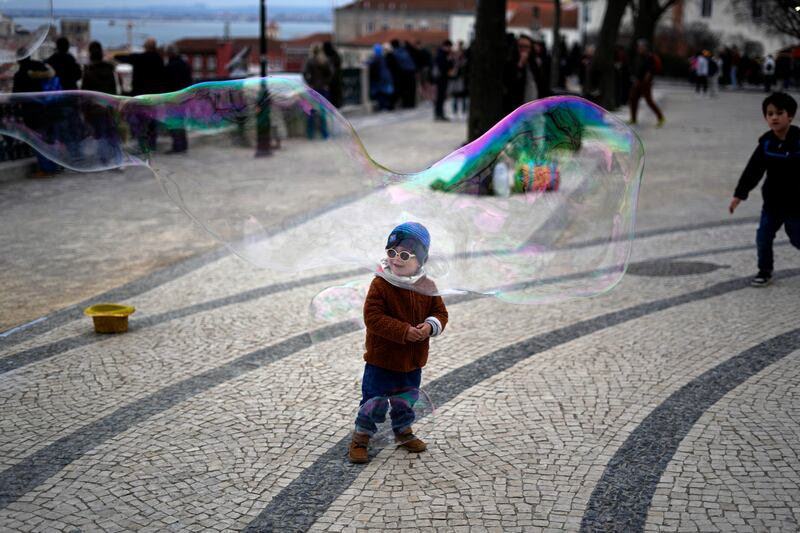 A child watches a street performer making soap bubbles at a public garden in Lisbon, Portugal. AP 
