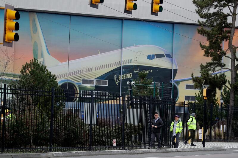 Workers walk away from the Boeing factory in Renton, Wash., where the company's 737 Max airplanes are built, with a painted exterior door of the factory in the background, Tuesday, Dec. 17, 2019. As Boeing prepares to shutter much of the huge factory near Seattle that builds the grounded 737 Max jet, the economic hit is reverberating across the United States. The 737 Max, which analysts say is the largest manufactured product exported from the U.S., was grounded worldwide in March 2019 after the second of two deadly crashes in Indonesia and Ethiopia that killed a total of 346 people, and on Monday, Dec. 16, 2019, Boeing announced that it would halt Max production in January 2020 with no date for it to resume. (AP Photo/Ted S. Warren)