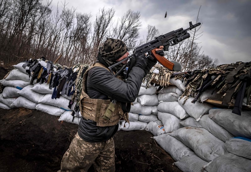 A Ukrainian soldier fires his rifle from a trench at the front east of Kharkiv in the north of Ukraine, which continues to be shelled by Russian forces. AFP