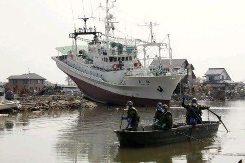 Members of the Self-Defense Forces search for missing people in front of a fishing boat stranded during the March 11 earthquake and tsunami in Higashimatsushima, Japan. Kimimasa Mayama / Bloomberg News