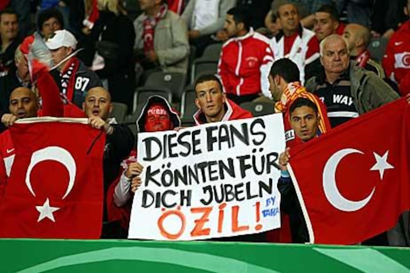 A Turkey fan lamenting his country's failure to persuade Mezut Ozil to play for the land of his parents instead of Germany, the land of his birth, holds up a sign reading: 'These fans could cheer for you Ozil!" during Turkey's recent 3-0 defeat to Germany in Berlin.