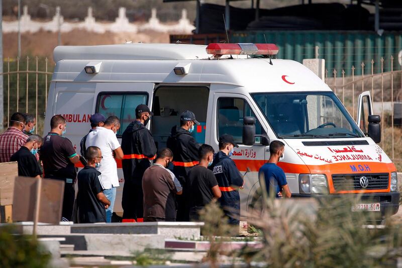 Palestinian health workers pray over the body of a doctor, who died from the coronavirus, ahead of his burial in a cemetery in the northern Gaza Strip. AFP