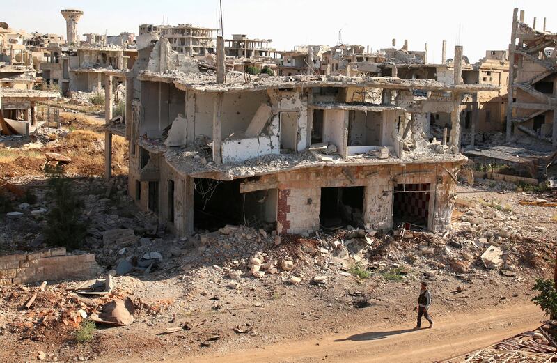 A fighter walks past damaged buildings in southern Syria (REUTERS/Alaa Al-Faqir/File Photo)