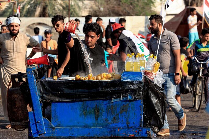 A volunteer street vendor prepares free corn cobs for anti-government protesters during a demonstration near Basra provincial council building, Iraq, Thursday, Oct. 31, 2019. (AP Photo/Nabil al-Jurani)