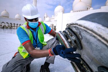 A workman sands the base of a carefully restored mosaic tile in the courtyard of Sheikh Zayed Grand Mosque. Victor Besa / The National