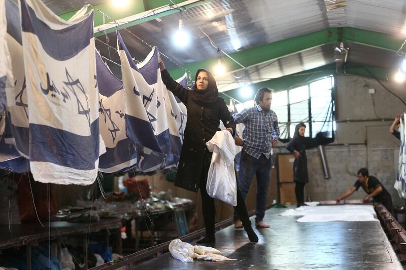 Iranian workers collect altered Israeli flags at a large factory that males US and Israeli flags for Iranian protesters to burn in Khomein City. West Asia News Agency via Reuters